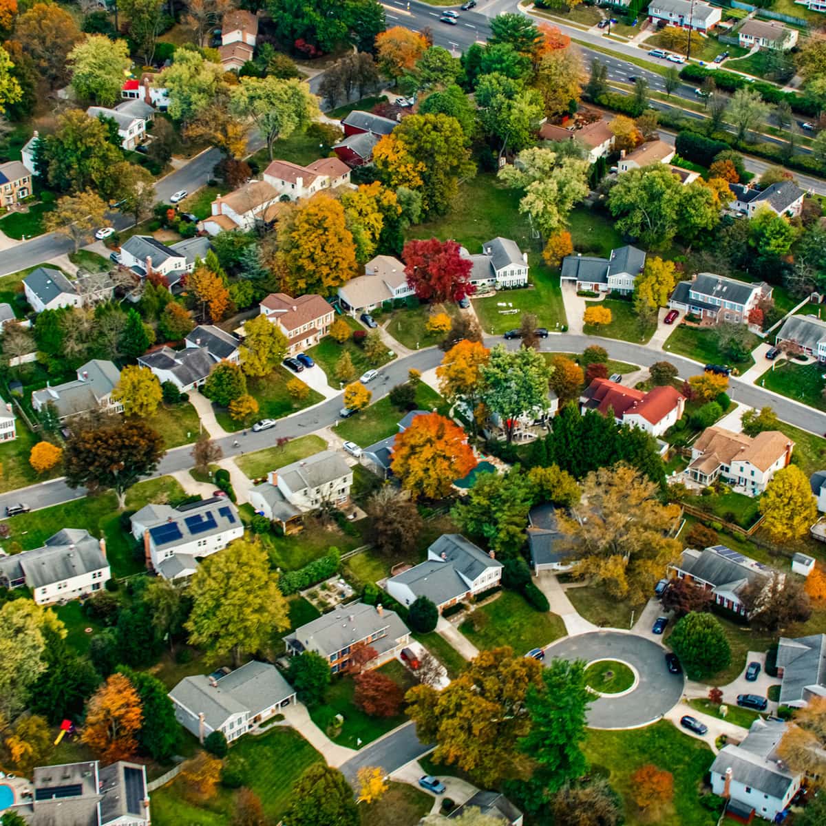An aerial view of houses in a community complex with fall foliage